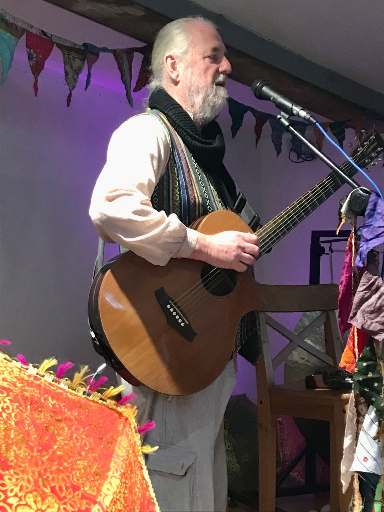 Andy playing guitar in an Arts Centre with bunting on the wall